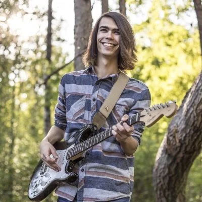 Adam Brousseau et sa guitare dans le sentier multifonctionnel de La Sarre