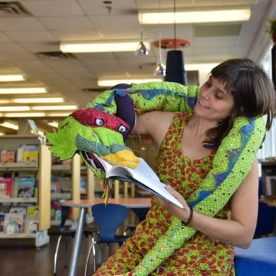 Fille regarde son serpent en peluche vert